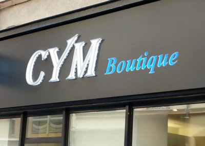 Vos enseignes à Lyon: Enseigne lumineuse avec caisson de façade et Drapeau double face à Lyon pour Cym Boutique (Lyon 69006) par SES (Grigny-Lyon)